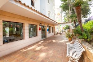 una pasarela con un banco blanco frente a un edificio en Flipflop Surfing Playa, en Santa Ponsa