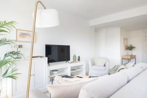 a white living room with a white couch and a tv at Apartamento La Nuez by Clabao in Pamplona