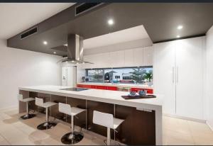 una cucina con mobili bianchi e un bancone con sgabelli di Seaside Luxury - Panoramic Views in Heart of Town a Ocean Grove