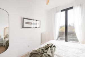 a white bedroom with a bed and a window at Apartamento La Nuez by Clabao in Pamplona