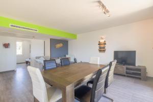 a dining room with a wooden table and chairs at Les Aloes - Appt climatisé vue mer et montagne in Calvi +6 photos