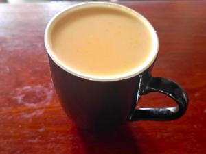 a black cup of coffee sitting on a wooden table at Oasis Hotel and Guest House. Voi in Voi