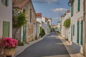 an empty street in a town with houses and flowers at Kampaoh Côte Sauvage in Saint-Clément-des-Baleines