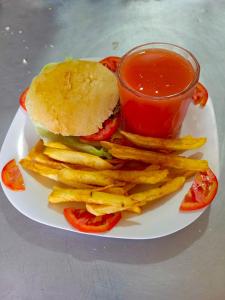 un plato con un sándwich y papas fritas y una taza de ketchup en Oasis Hotel and Guest House. Voi, en Voi