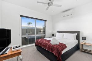 a bedroom with a bed and a large window at Sunset Days Family Holiday House 200m to Shops in Ocean Grove
