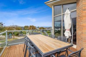 a deck with a wooden table and chairs on a balcony at Stunning ocean views indoor spa and sun deck in Torquay