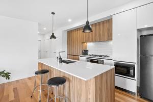 a kitchen with a white counter and stools at Boardwalk on Bright Coastal Apartment in Torquay