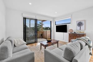 a living room with two couches and a tv at Boardwalk on Bright Coastal Apartment in Torquay