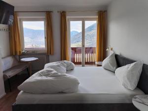 a bedroom with a large white bed with two windows at Plarserhof in Lagundo