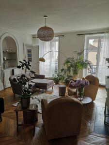 un soggiorno con divani, tavoli e piante di Lumière & Majesté Appartement Versailles a Versailles