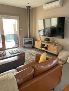 sala de estar con sofá de cuero marrón y TV de pantalla plana en Over the dunes to the beach in seconds, en Ocean Grove