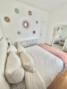 Apartment near to Paris (7 minutes) في أسنيير-سور-سين: غرفة نوم بيضاء مع سرير ومرآة