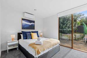 a bedroom with a bed and a large window at Coastal Class and Sophistication 500m to Beach in Ocean Grove +6 photos