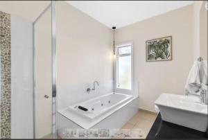 a white bathroom with a tub and a sink at The Briars 450m to Torquay Front Beach in Torquay