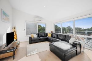 a living room with a black leather couch and a television at Seaworthy Sanctuary Jan Juc in Torquay