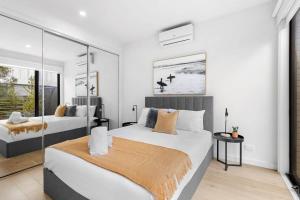 2 Betten in einem Schlafzimmer mit weißen Wänden und Fenstern in der Unterkunft Torquay Central Beach Retreat in Torquay