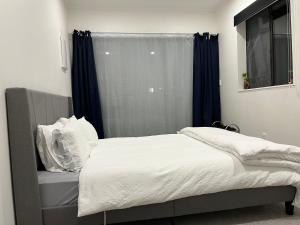 a bedroom with a bed and a window with blue curtains at Totara Vale, Free Coffee, parking and wifi, near Glenfield Mall and highway 18,1 in Auckland