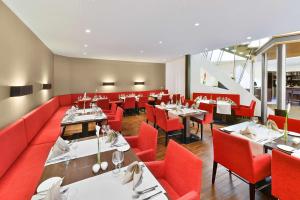 un restaurante con sofás rojos, mesas y sillas en NH Mannheim Viernheim, en Viernheim
