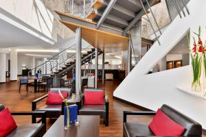 een lobby met stoelen, tafels en trappen bij NH Mannheim Viernheim in Viernheim