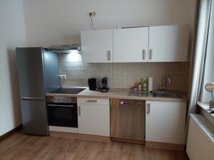 a kitchen with white cabinets and a black refrigerator at Cozy Home, 7 Beds, WiFi, Kitchen, Balcony, Bielefeld Center in Bielefeld