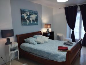 Schlafzimmer mit einem Bett mit blauer Bettwäsche und Kissen in der Unterkunft L'Écluse in Dieppe