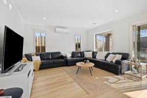 a living room with a black couch and a tv at Park Front Villa with sparkling swimming pool in Saint Leonards +12 photos