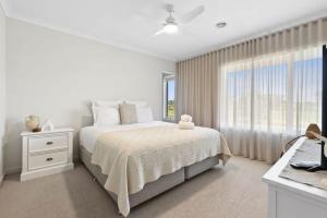 a white bedroom with a bed and a window at Park Front Villa with sparkling swimming pool in Saint Leonards