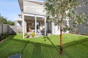 a yard with a small tree in front of a house at Saltbush By The Park in Torquay