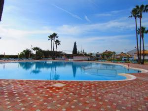 a large swimming pool with palm trees in the background at Apartment Golden in Tavira