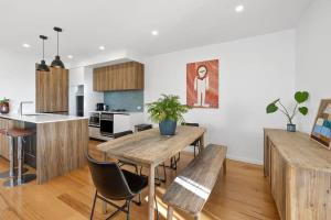 a kitchen and living room with a wooden table and chairs at Saltbush By The Park in Torquay