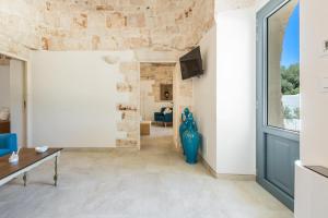 uma sala de estar com uma parede de pedra e um vaso azul em Trulli Ulivo di Puglia by Perle di Puglia em Selva di Fasano