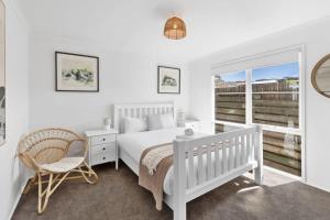 a bedroom with a white bed and a chair and a window at Blue Seas Beach House, 400 metres to the beach in Ocean Grove +12 photos