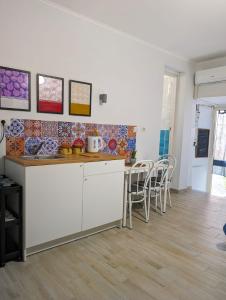 een keuken met witte kasten en een tafel en stoelen bij La Sartoria - Casetta napoletana in Napels