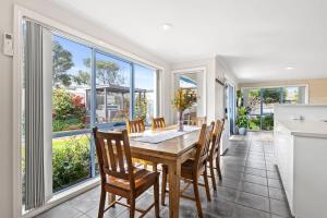 a dining room with a table and chairs and windows at Coastal Serenity Central Torquay in Torquay