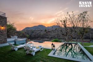 une personne debout à côté d'une piscine dans une cour dans l'établissement StayVista's Ikebana - Living By The Forest Edge - Mountain-view Villa with Infinity Pool, Lawn, & Indoor-Outdoor Games, à Udaipur