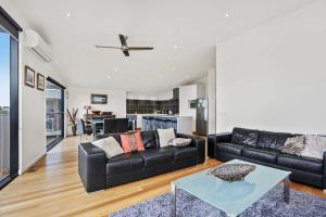 a living room with a black couch and a table at Seaview Sanctuary Jan Juc Distant Ocean View in Torquay