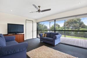 sala de estar con 2 sillas azules y TV de pantalla plana en Seaview Sanctuary Jan Juc Distant Ocean View, en Torquay