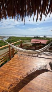 eine Holzterrasse mit einer Hängematte am Strand in der Unterkunft Villas del Mar in Las Tunas