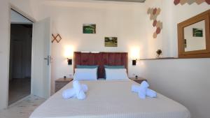 a bedroom with a large white bed with two pillows at Wave Sound Apartments - Village View in Skala Marion