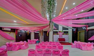 a room with pink chairs and a ceiling with curtains at Treebo Bliss in Jaipur