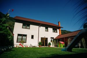 una casa blanca con un parque infantil delante de ella en Vila Rodica Transalpina, en Şugag