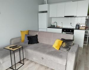 a living room with a couch with pillows and a table at Ukiel Park J&J in Olsztyn