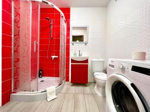 a red bathroom with a shower and a washing machine at ApartPoltava Затишна квартира в новобудові, панорамний балкон, банківський чек in Poltava