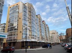 a large building on a city street with parked cars at ApartPoltava Затишна квартира в новобудові, панорамний балкон, банківський чек in Poltava