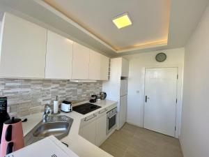 a kitchen with white cabinets and a sink at Old Town Famous Aparts in Antalya