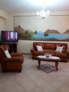 ein Wohnzimmer mit Sofas und einem Flachbild-TV in der Unterkunft PERLA VERDE Camere con bagno privato in Patti