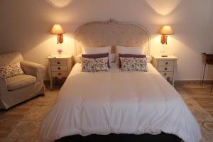 ein Schlafzimmer mit einem weißen Bett mit Kissen und einem Stuhl in der Unterkunft La Casa de la Vieja - Alojamiento Rural 3 y 4 Estrellas in Belmonte