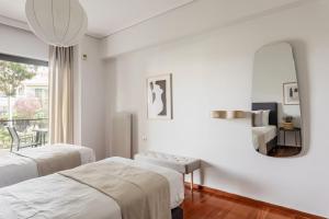 ein weißes Zimmer mit 2 Betten und einem Spiegel in der Unterkunft Chic & Luminous 3BR Apartment in Kifisia by UPSTREET in Athen