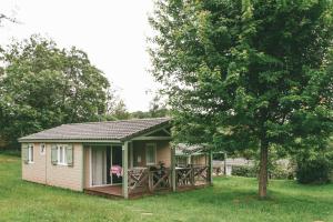 une petite maison avec une véranda et un arbre dans l'établissement Terres de France - Les Hameaux de Miel, à Beynat