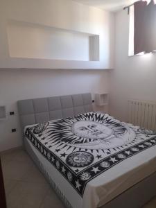 a bed with a black and white blanket on it at Appartamento Ogliastra in Lanusei